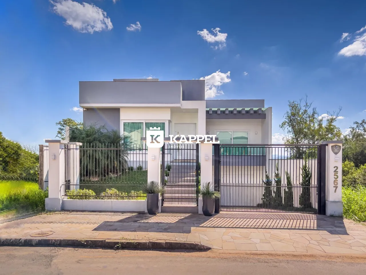 Fachada de uma residência moderna com cerca e paisagismo em Lajeado, Brasil.
