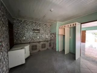 Interior de uma área com revestimento de azulejos e armários brancos.