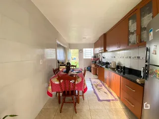 Uma sala de jantar com mesa de madeira e cozinha em um imóvel no Brasil.