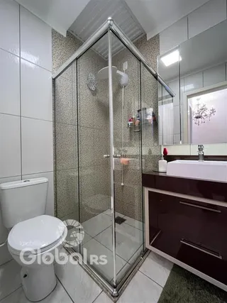 Banheiro com box de vidro e louças brancas.