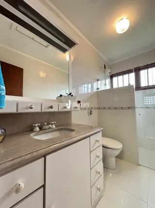 Foto de um banheiro com bancada e revestimento branco.