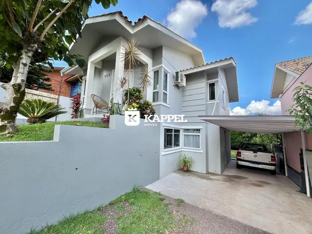 Fachada de uma casa em Lajeado, Brasil, com revestimento cinza claro e jardim frontal.