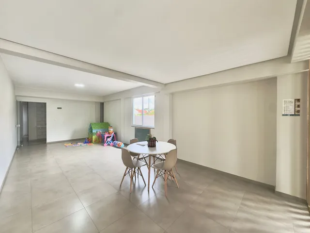 Uma sala de jantar ampla com mesa redonda e janela de vista para o exterior.
