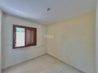 A foto mostra o interior de uma sala com piso de cerâmica e uma janela.