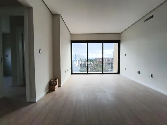 Ambiente interno de uma sala com piso de madeira e grande janela.
