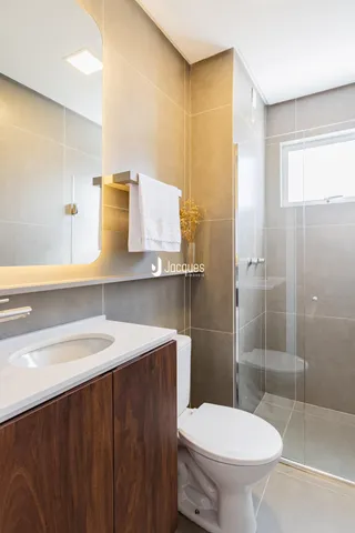 Banheiro moderno com revestimento de cerâmica e box de vidro.