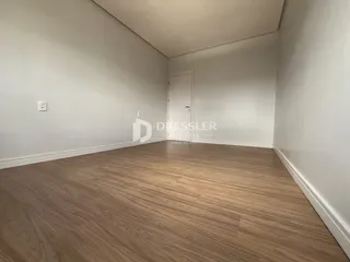 Foto de um cômodo interno com piso de madeira clara e paredes brancas.