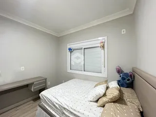 Quarto com cama e janela em ambiente claro.