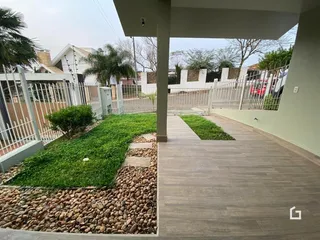 Fachada de uma casa com jardim e área de lazer.