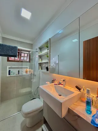 Banheiro moderno com box de vidro e bancada de mármore.