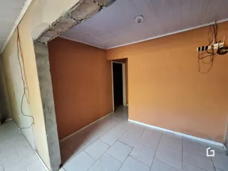 Interior de uma sala com parede de tijolo aparente e piso cerâmico.