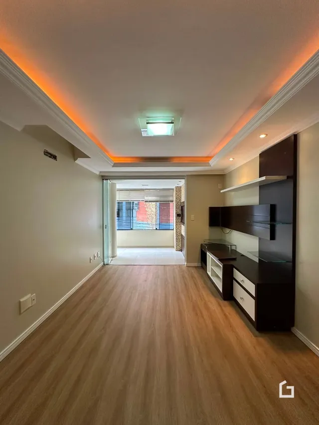 Corredor interno de uma residência com piso de madeira clara.