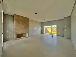 Sala de estar ampla com piso claro e parede de destaque em tijolo aparente.