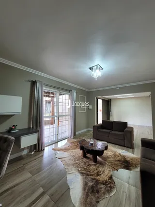 Sala de estar com piso de madeira e portas de vidro que dão acesso ao exterior.