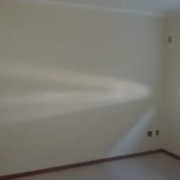 Parede interna clara com piso de madeira em um ambiente residencial.