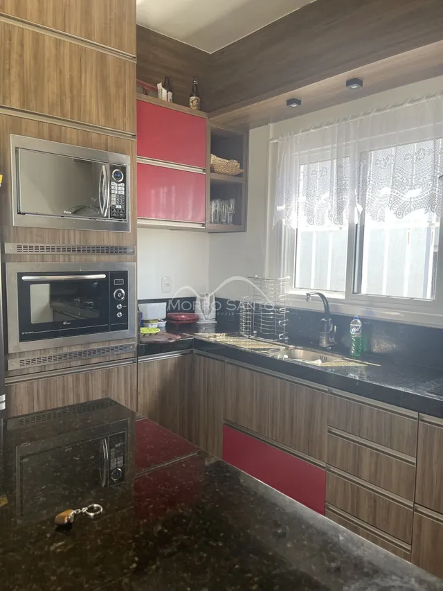 Cozinha com armários de madeira e bancada escura em imóvel em Lajeado.