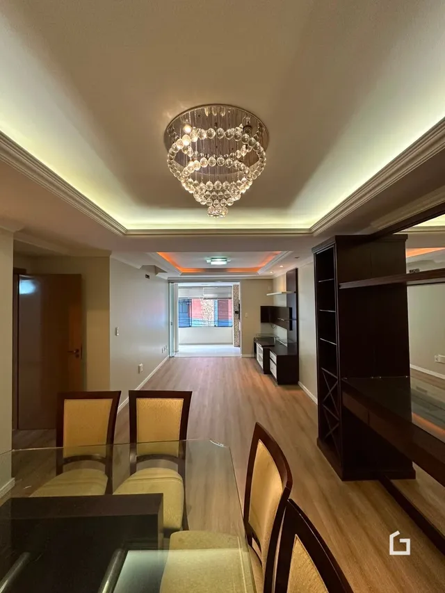 Uma sala com piso de madeira e lustre decorativo.