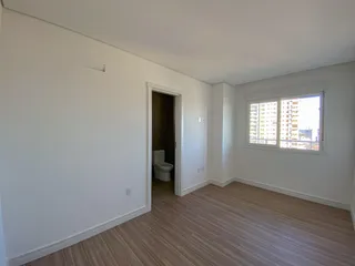 Foto de uma sala com piso de madeira e uma janela mostrando um prédio urbano.