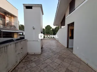 Pátio externo pavimentado entre duas edificações brancas em Lajeado.