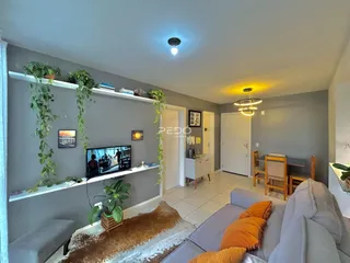 Sala de estar com decoração verde e sofá cinza na residência.