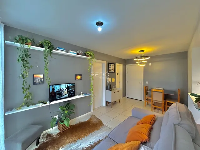 Sala de estar com decoração verde e sofá cinza na residência.
