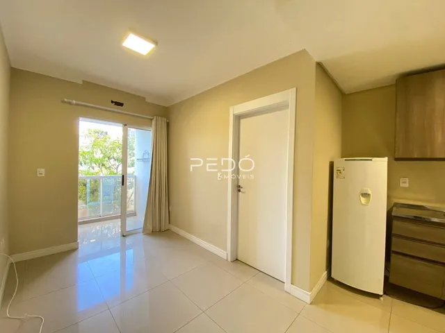 Sala de estar com piso de cerâmica clara e porta de vidro abrindo para a varanda.