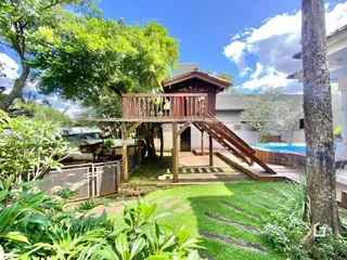 Vista externa de uma propriedade com jardim e estrutura de madeira.