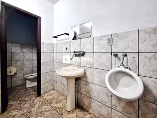 Banheiro com revestimento de azulejos claros e pia de pedestal.