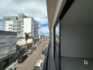 Vista da rua em Lajeado, Brasil, mostrando edifícios residenciais e veículos.