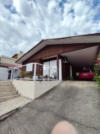 Fachada de uma residência com estrutura de telhado e muro de contenção.