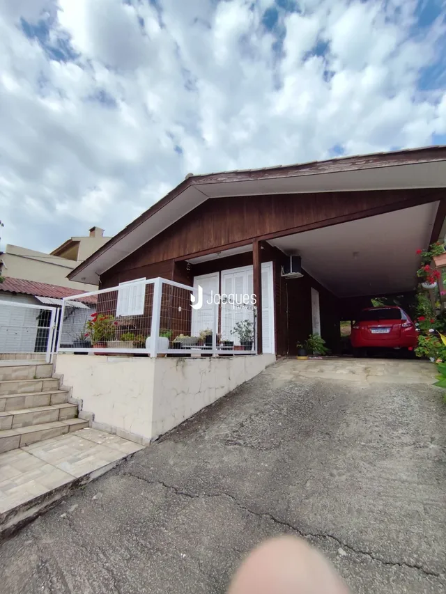 Fachada de uma residência com estrutura de telhado e muro de contenção.