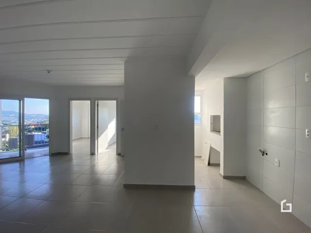Interior de uma sala ampla com paredes brancas e teto alto.