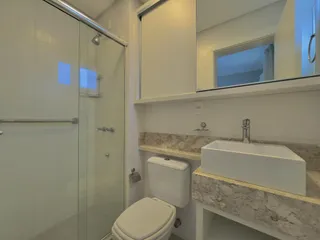 Foto interna de um banheiro com box de vidro e bancada de mármore.