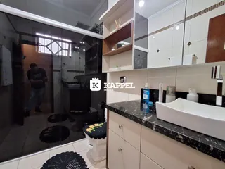 Cozinha moderna com bancadas escuras e armários brancos.