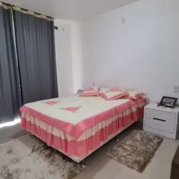 Quarto com cama e roupa de cama rosa em um imóvel.