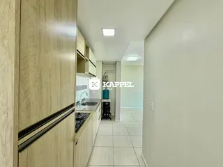 Foto de uma cozinha com armários e piso de cerâmica em um corredor claro.