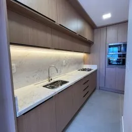 Cozinha com armários de madeira e bancada clara.
