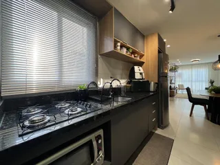 Vista da cozinha moderna com bancada escura e armários em Lajeado, Brasil.