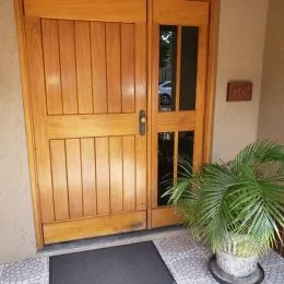 Porta de madeira com painéis verticais na entrada da propriedade.