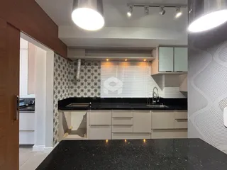 Uma cozinha moderna com armários claros e bancadas escuras.
