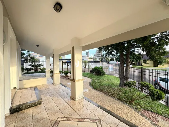 Vista externa de um pátio coberto com piso de cerâmica e jardim em Lajeado.