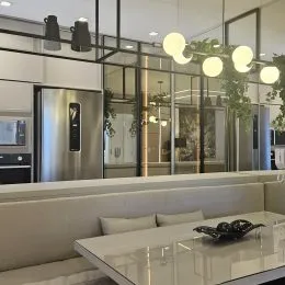 Sala de estar moderna com grandes painéis de vidro e sofá claro.