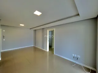 Interior de uma sala com paredes brancas e piso claro.