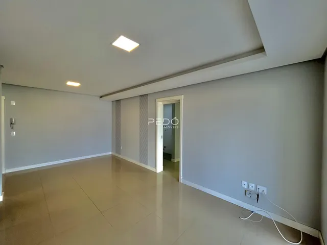 Interior de uma sala com paredes brancas e piso claro.