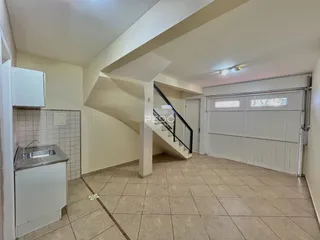 Imagem de uma área interna de uma residência com piso de cerâmica e armários brancos.