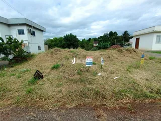 Vista externa de uma propriedade com um monte de vegetação seca no primeiro plano.