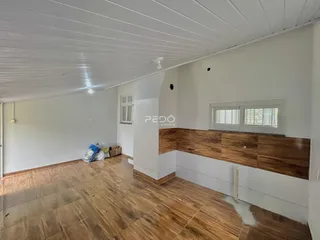 Vista interna de um ambiente com piso de madeira e paredes brancas.