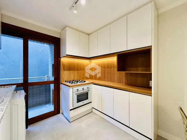 Cozinha moderna com armários brancos e detalhes em madeira.