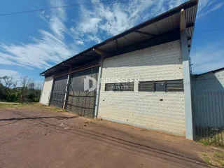 Vista externa de um galpão industrial com revestimento de telhas metálicas e portão de metal.