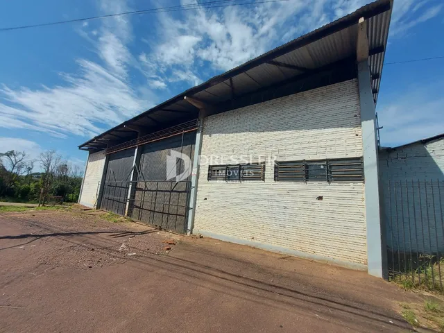 Vista externa de um galpão industrial com revestimento de telhas metálicas e portão de metal.